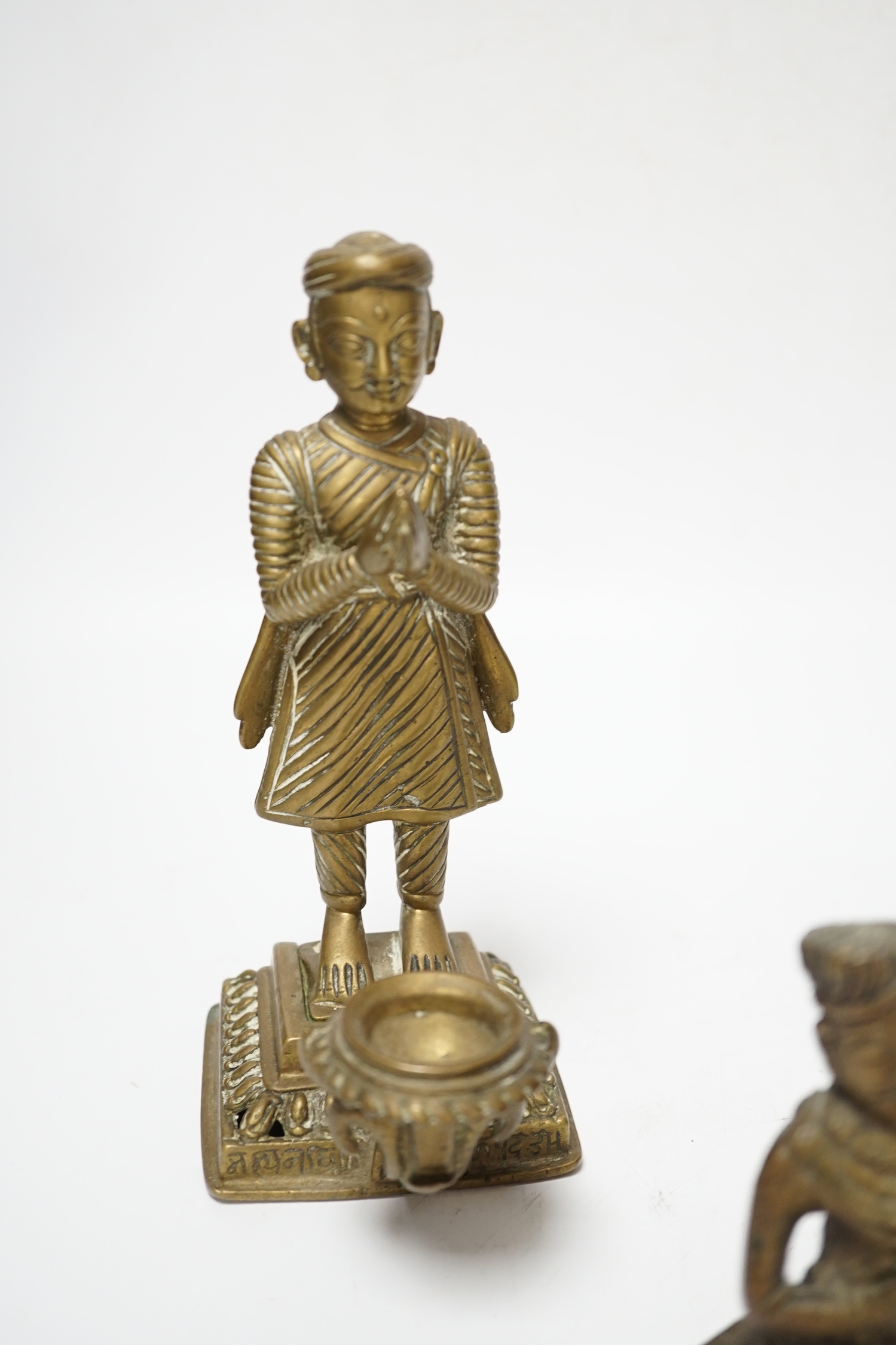 Three Nepalese figural brass oil lamps, 18th/19th century